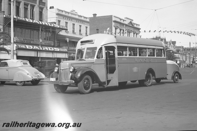 P23174
Western Australian Government Railways bus, licence 31705, with trailer, bound for Kojonup, outside Baird's store and the Globe Hotel, front and side view from ground level
