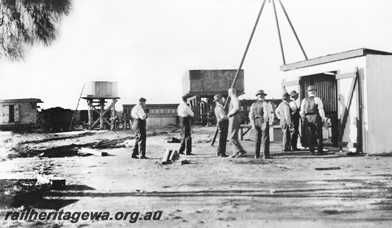 P23245
 Small shed with men gathered in front of, a pair of water towers, one with a squatters tank and the other with a 25,000 gallon cast iron tank, Commissioners inspection tour. Parroo. NR line
