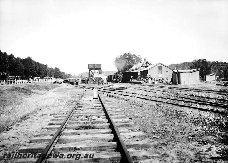 P23265
Station building, water tower with cast iron tank, steam locomotive hauled train in station. Army personell on the platform, Gingin, MR line., view looking along the track
