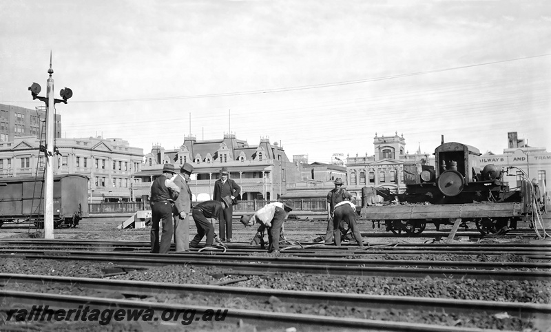 P23297
Gangers working on the track near Perth Station with compressor mounted on a H wagon. In the background is the Royal Hotel crn Wellington Street and William Streets, Foggitt Jones and Railways and Tramways Institute buildings. ER line
