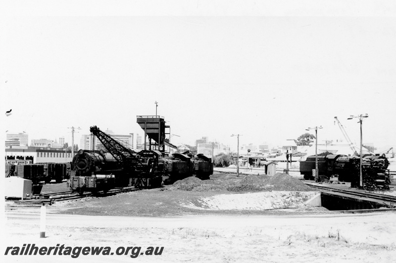 P23356
1 of 2 views of the temporary loco depot at East Perth, V class 1224, steam crane other locomotives, H class 908 4 wheel open wagon, coaling stage, turntable, overall view of the depot
