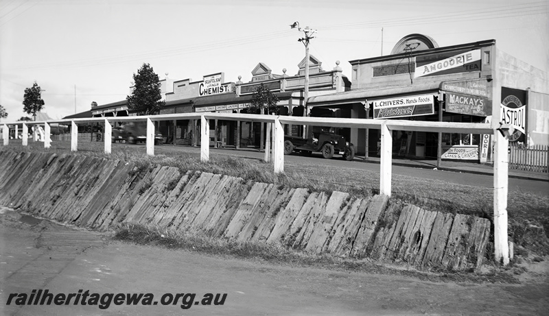 P23451
Shops, road, vehicles, wooden fence, sleeper retaining wall, Bayswater ER line, view from footbridge
