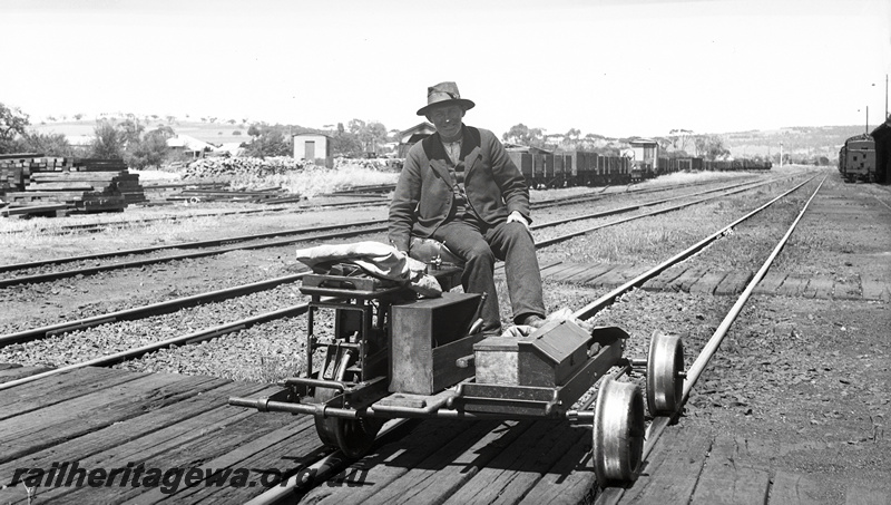 P23455
Motorised trolley with man, in yard, tracks, wagons, sleeper crossing, end view from trackside
