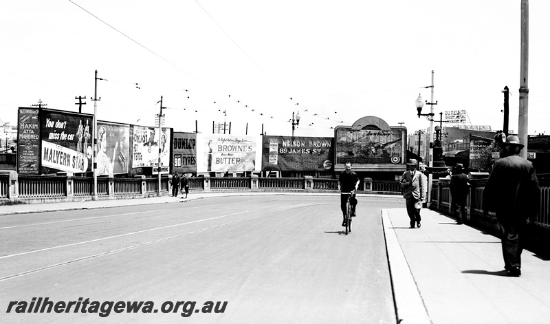 P23480
Advertising signs, cyclist, pedestrian, William St Horseshoe Bridge, Perth, ER line, view from roadway
