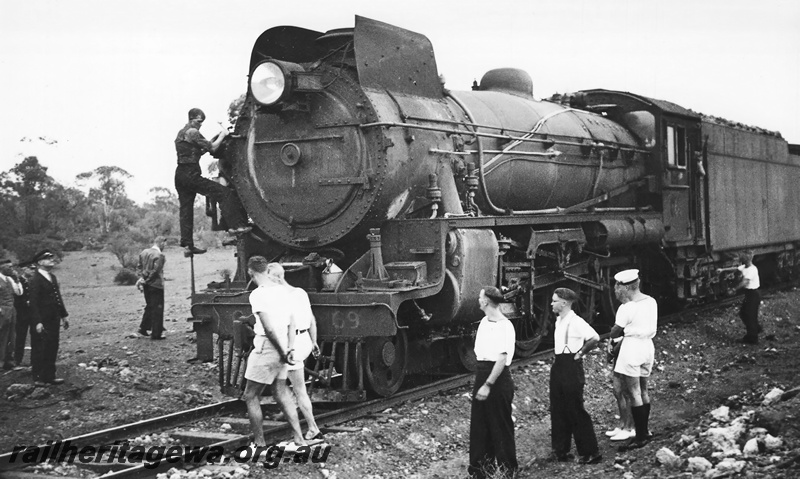 P23539
Commonwealth Railways C class 69 hauling a troop train  on the Nullarbor.  Both sailors and airmen were passengers, some are depicted looking at the locomotive.
