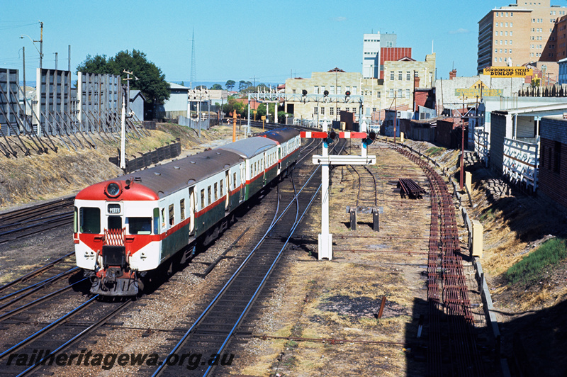 P23879
ADG class railcar, on 3 car DMU set, bracket signals, colour light signals, signal gantry, trackside rodding, city buildings, Perth, end and side view from elevated position
