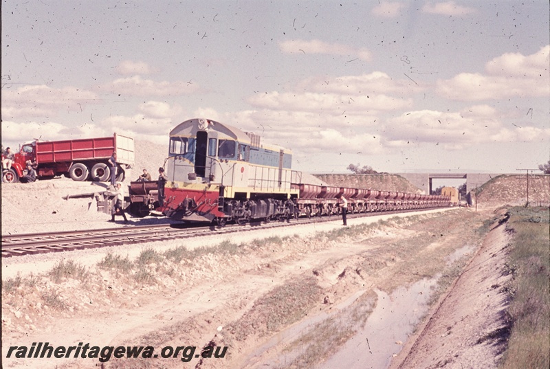 T04643
J class 101 standard gauge diesel locomotive at the head of a ballast train of 4 wheeled wagons at Kenwick with wagons on an adjacent line being loaded with ballast.
