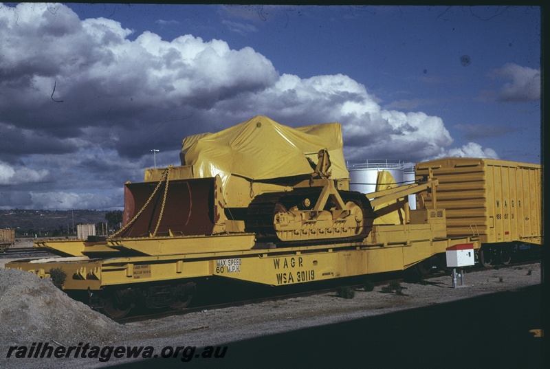 T04648
WSA class 30119 standard gauge flat top loaded with a 'Wreckmaster' tractor pictured at Forrestfield. This equipment was used in derailment recovery.
