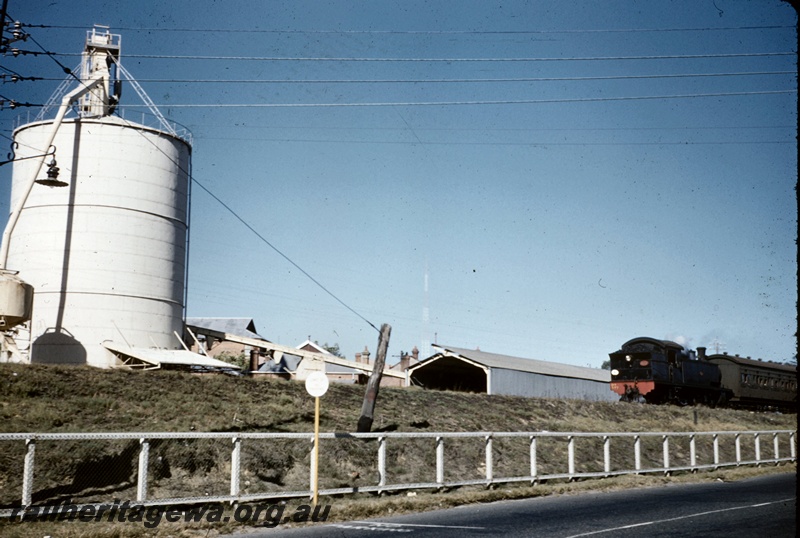 T05061
DS class 377 bunker first, on Royal Show Special, silo, conveyor, shed, roof tops, white wooden and mesh fence, photo taken from adjacent roadway, West Perth, ER line

