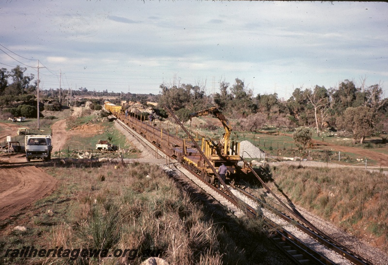 T05092
Track replacement machine P811 at work, flat wagon, wagons, van, on works train, road crossing, in Cockburn to Kwinana section, view along train from rear
