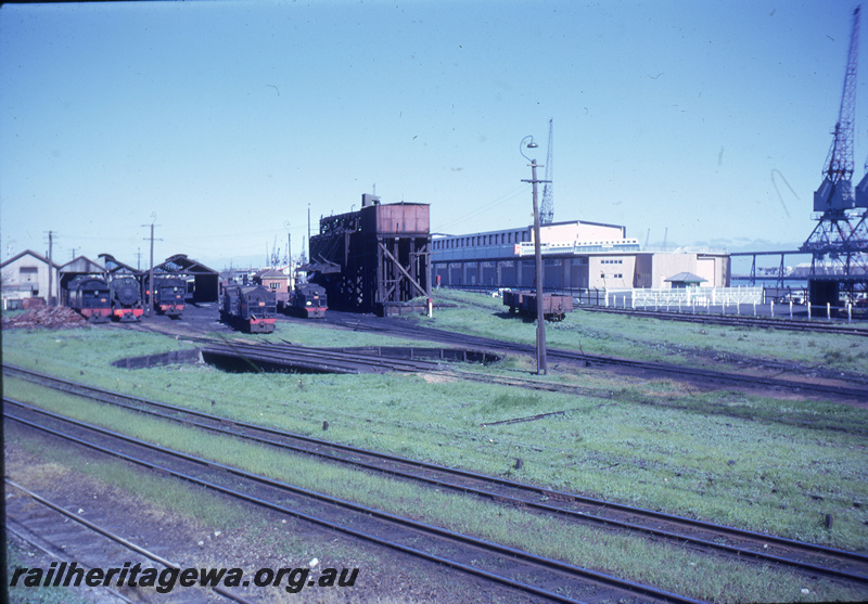 T05653
Fremantle Locomotive Depot -  showing turntable and various locomotives G,  K, Ds, Pmr class locomotives. Coaling stage , water tanks and running shed in background. Fremantle Port Authority's passenger terminal to right of photo. ER line
