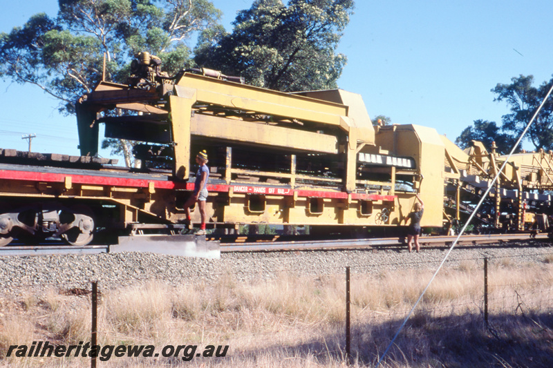 T05784
4 of 8 views of the work on the Kalgoorlie to Kwinana Rehabilitation Project featuring the P811 Track Replacement Machine. Sleepers being removed from the wagons being placed on the roadbed.
