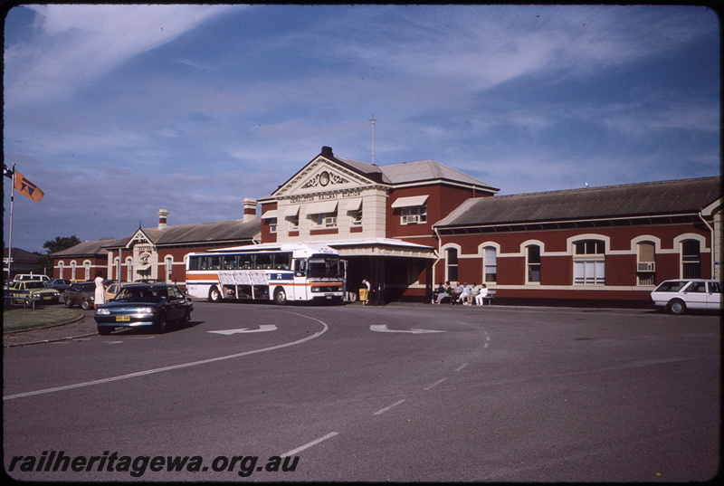T08513
Geraldton station building and forecourt, Westrail bus M184, Westrail flag, NR line
